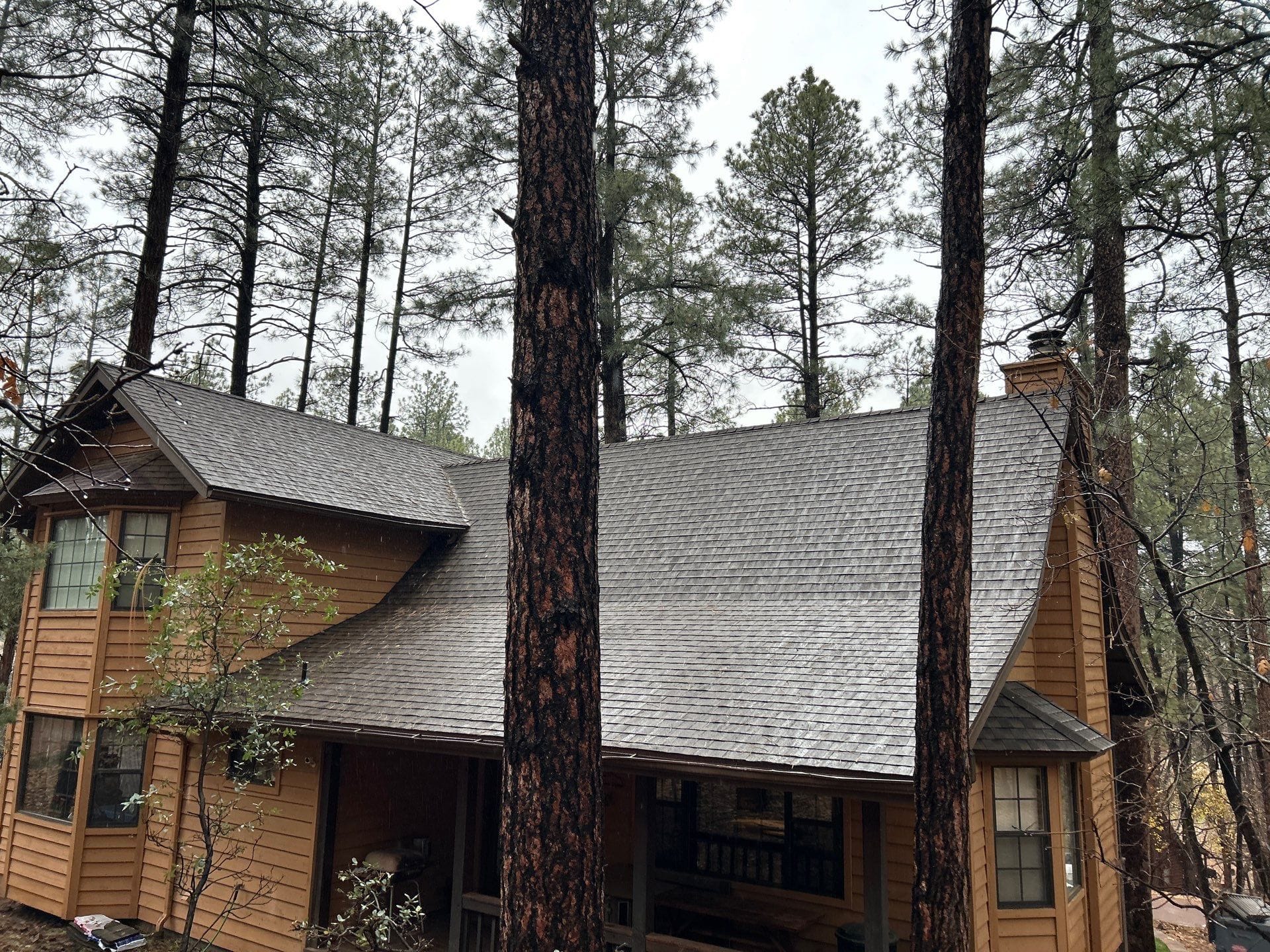 Finished gray architectural shingle roof plane running up to the ridge line on a cabin in Pine, Arizona