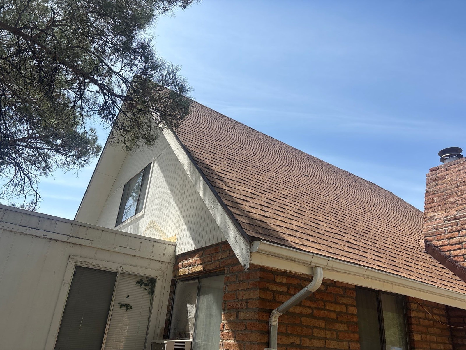 Close view of a new brown architectural shingle roof and brick chimney on a home in Safford, Arizona