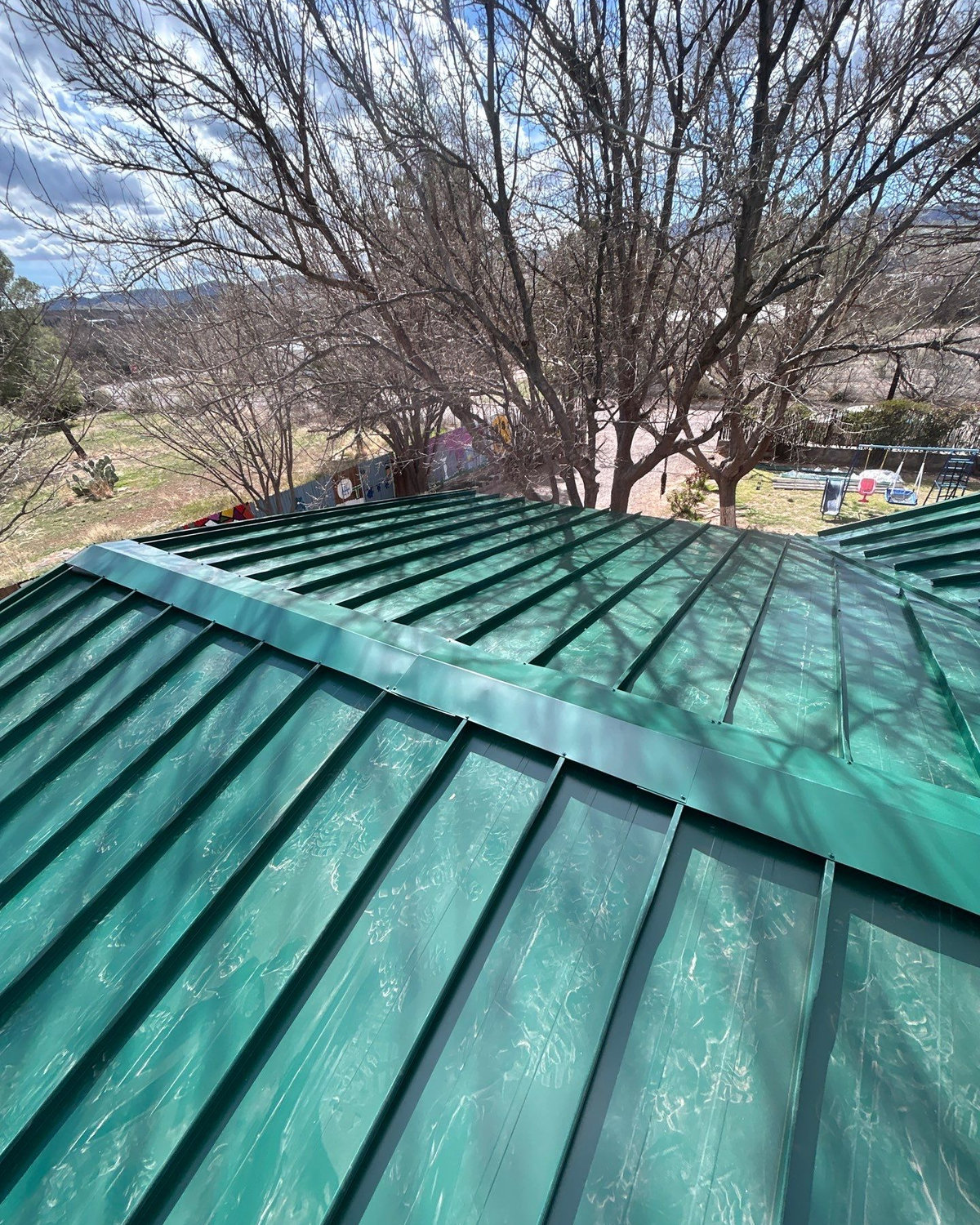 Green metal roof under pines